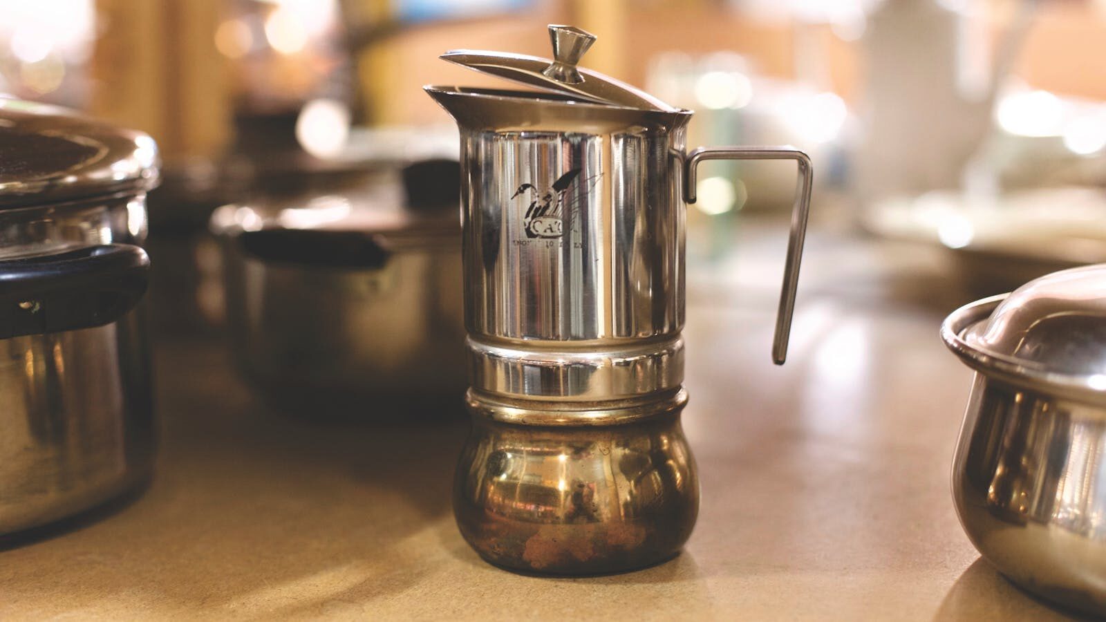 Close-up of a vintage stainless steel coffee maker on a kitchen counter.
