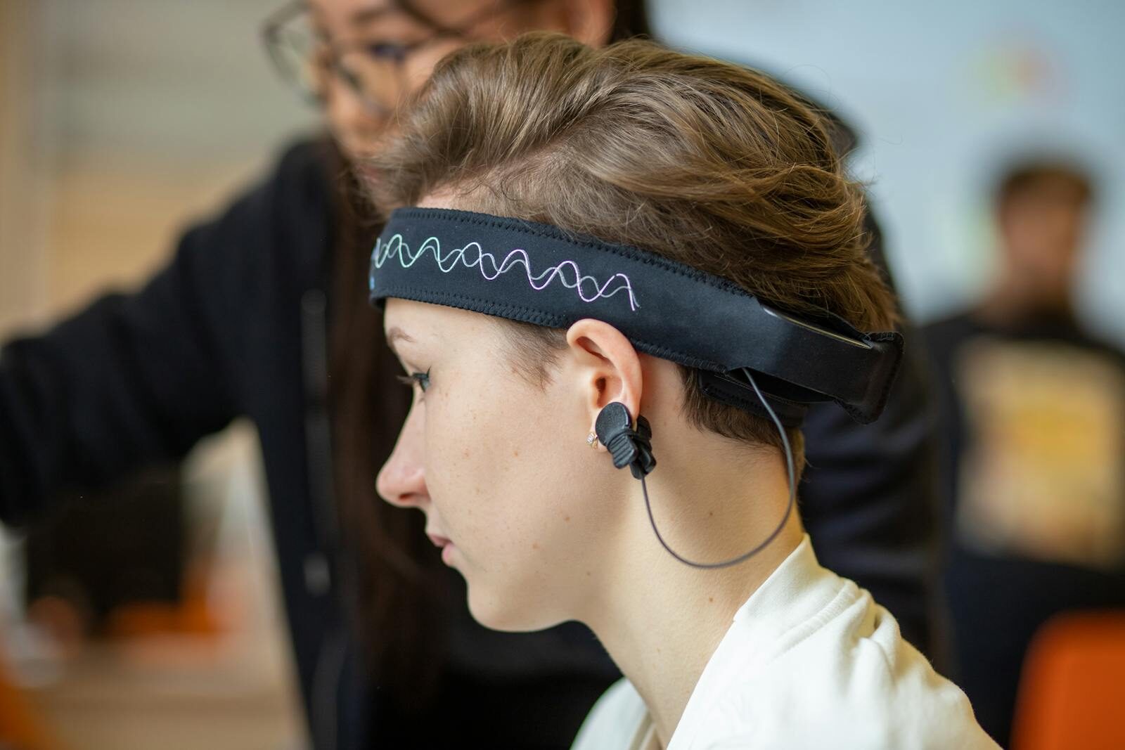 Close-up of a young woman wearing an EEG headband, showcasing modern technology indoors.