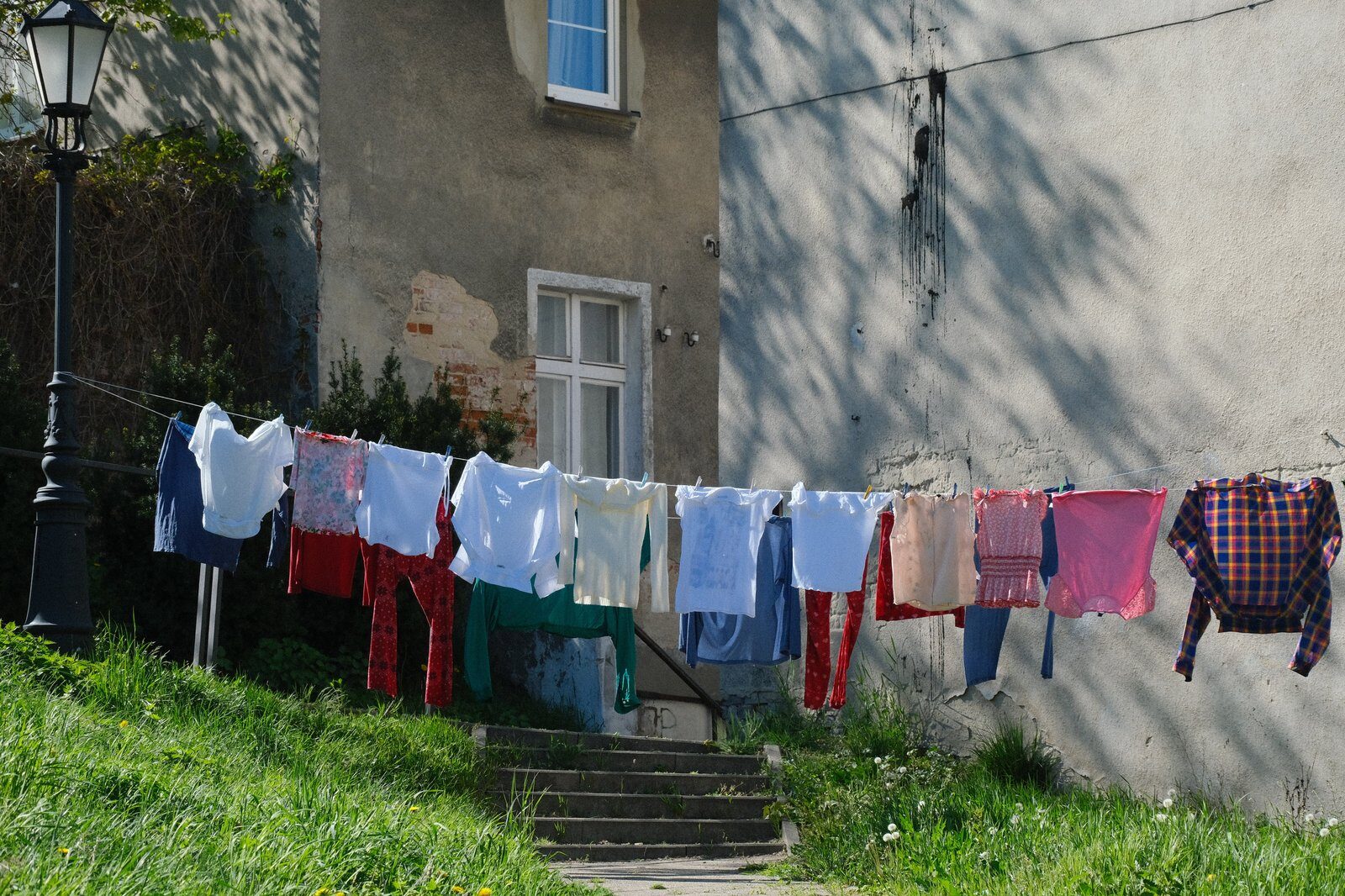 Vibrant clothes hanging on a line outside a rustic building on a sunny day.