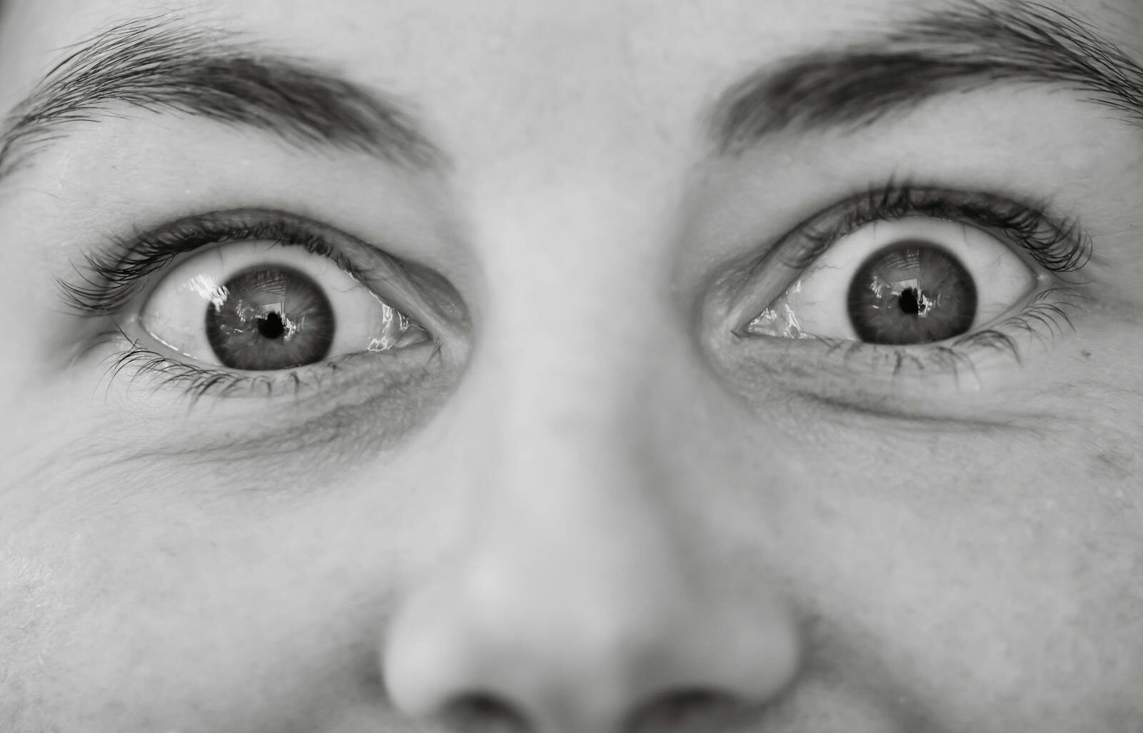 Black and white close-up of wide open eyes conveying surprise.