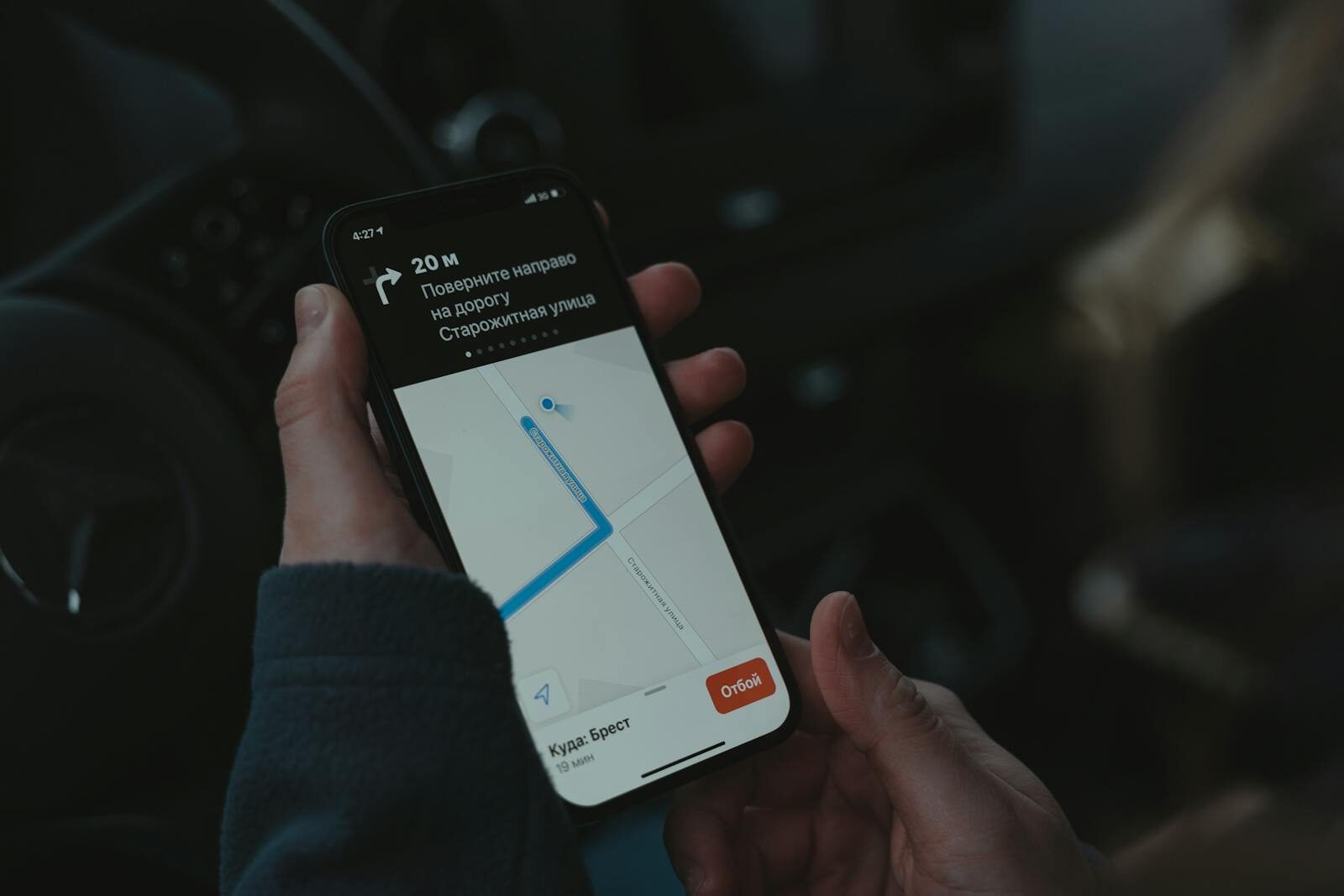 Close-up of a smartphone displaying a navigation app in a car, highlighting modern technology use while driving.