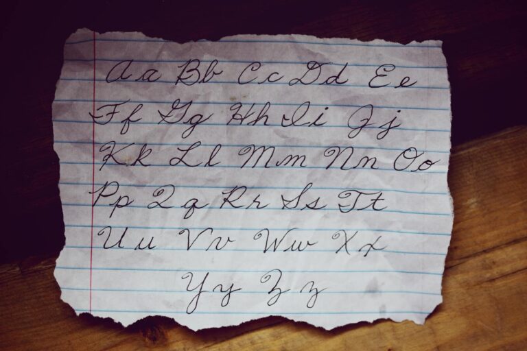 A close-up of cursive alphabet letters beautifully written on lined paper, showcasing elegant handwriting.