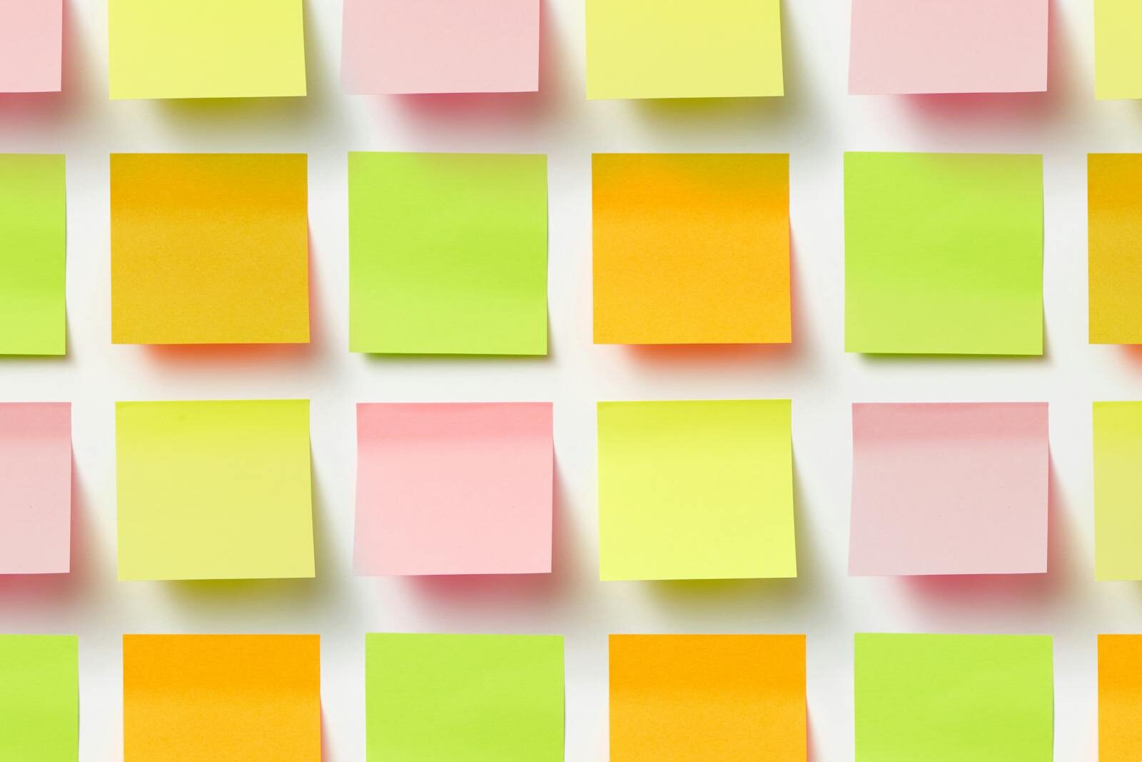 Grid of colorful sticky notes creating a vibrant pattern on a white surface.