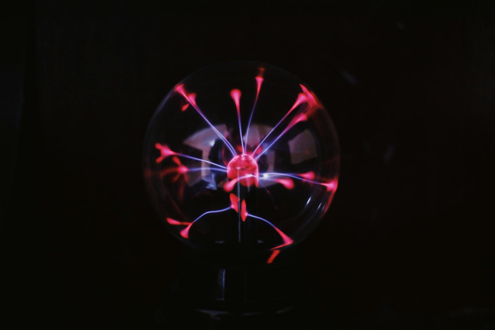 Crystal glass plasma ball with glowing electric lights inside placed in dark room